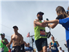 Runner with a beard and sunglasses smiles as he gives kids high fives with both hands