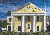 image of an historic house with yellow wood clapboards and white trim including columns