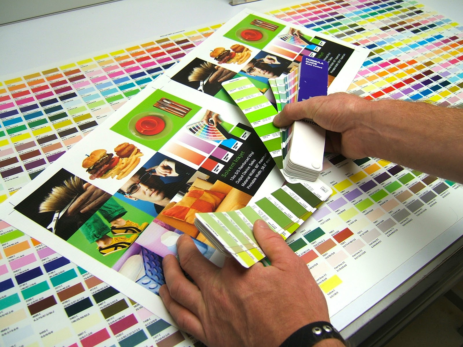 colorful image of hands holding a graphic layout surrounded by color swatches