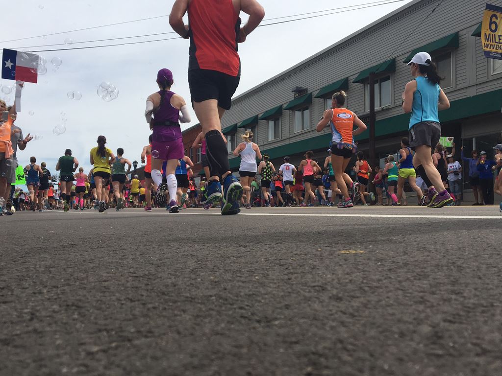 Image of runners backs from an angle on the ground facing buildings on Waverly Street